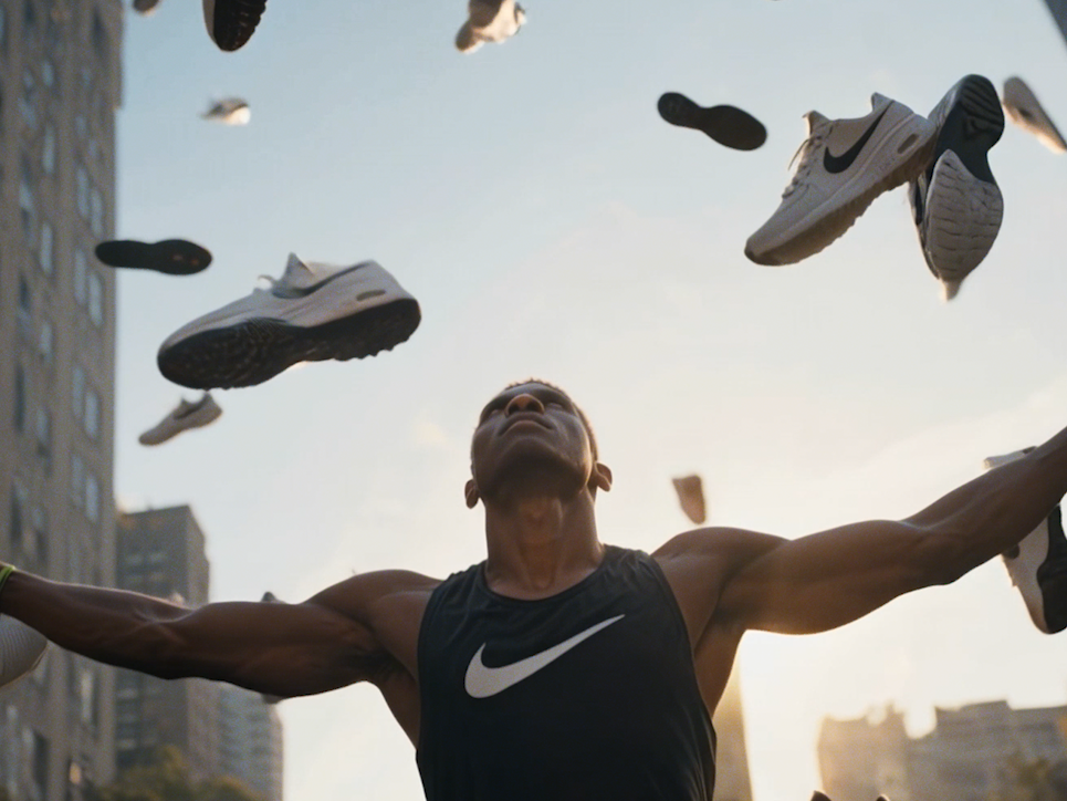 nike athlete raises arms as sneakers and soles rain down in a city sunset.